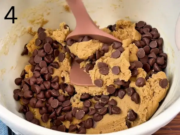 Folding chocolate chips into soft cookie dough evenly