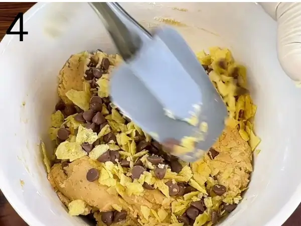 Folding chocolate chips and crushed potato chips into dough