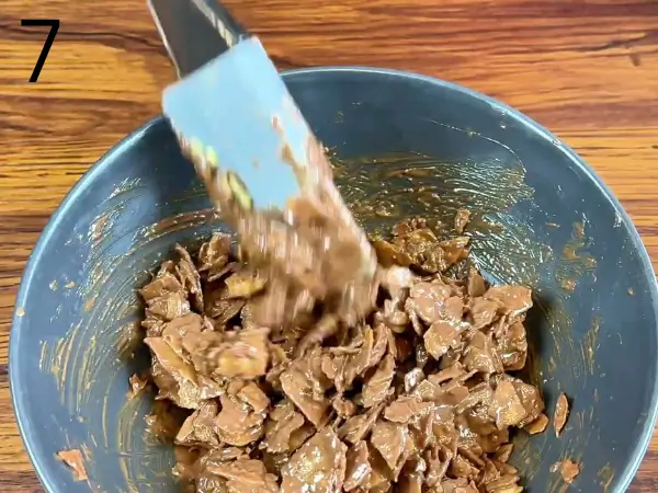 Mixing melted chocolate with crushed chips for crunchy topping