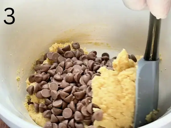 Adding chocolate chips to the cookie mixture