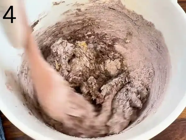Combining wet and dry ingredients to form chocolate coffee cookie dough.