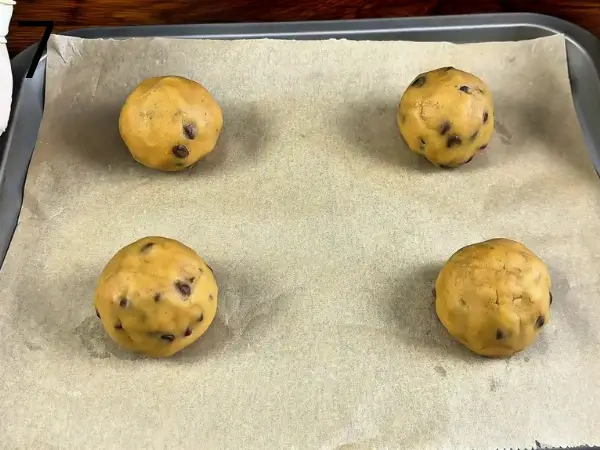 Chilled Nutella-filled cookie dough balls arranged on a baking tray before baking.