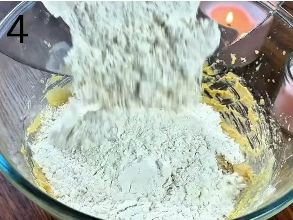 Combining the dry ingredients with the wet ingredients to make cookie dough.