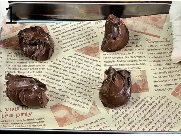 Scooping Nutella onto a parchment-lined baking tray before freezing.