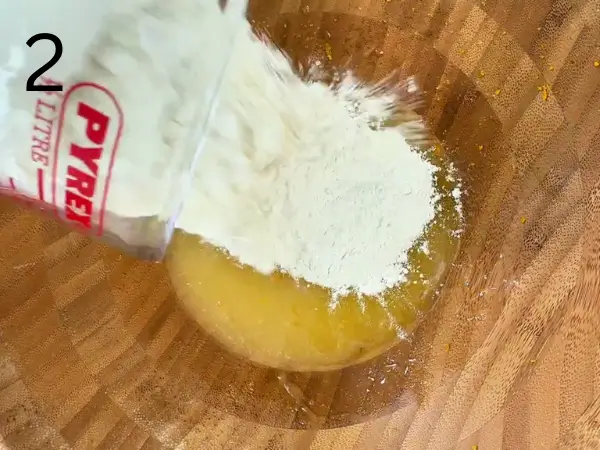 Adding flour, shredded coconut, orange zest, and baking powder to the cookie dough