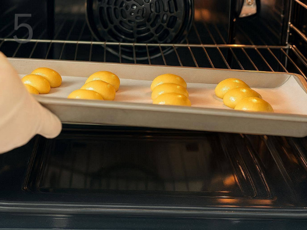Unbaked cookie dough balls arranged on a parchment-lined baking tray