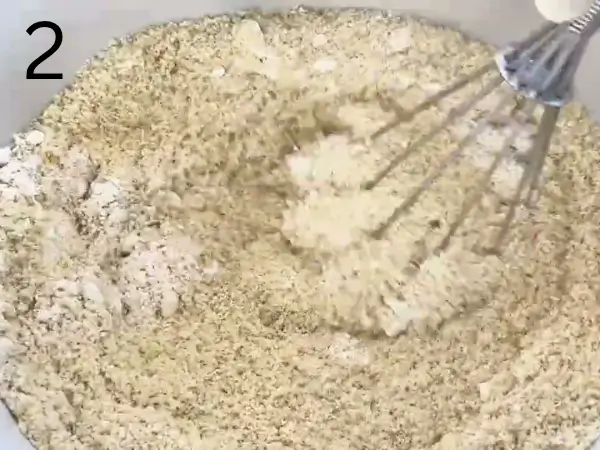 Flour, ground almonds, baking powder, and salt being added to the butter mixture to make Almond Croissant Cookies dough.
