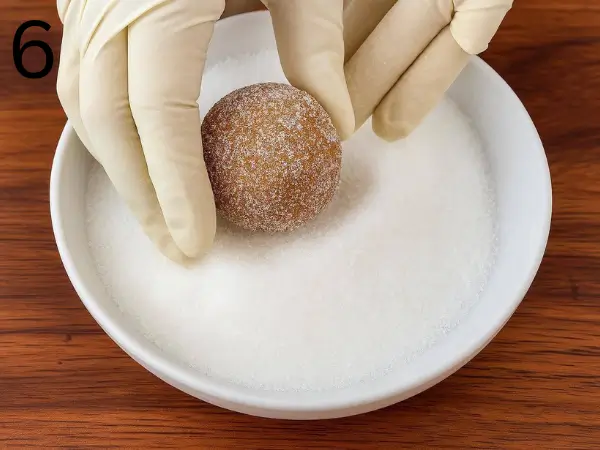 Cookie dough balls placed on a parchment-lined baking tray with small indentations in the center.