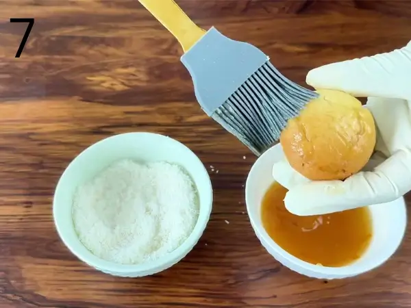 Coating baked cookies with orange jam before adding shredded coconut